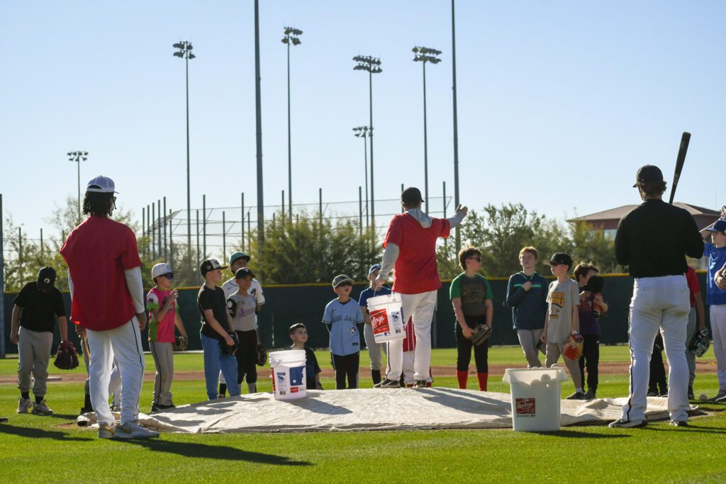 A group of children and adults engaged in an outdoor activity with buckets and a rope.