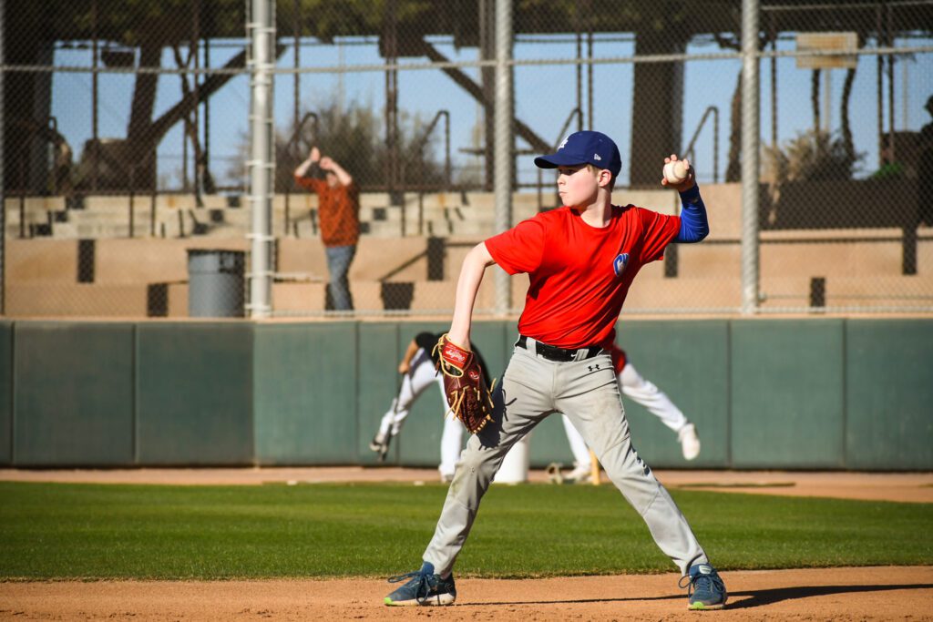 Young baseball player pitching during a game on a sunny day.
