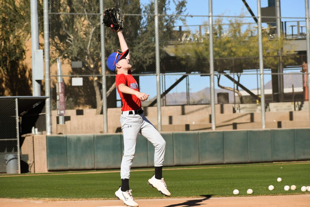 Baseball player jumping to catch a ball on the field.
