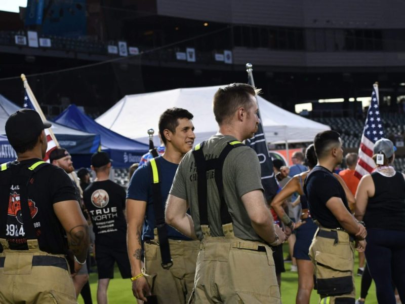 Firefighters in gear at an outdoor event during nighttime.