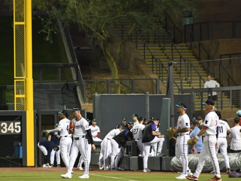 Baseball players gathering near the dugout during a game.