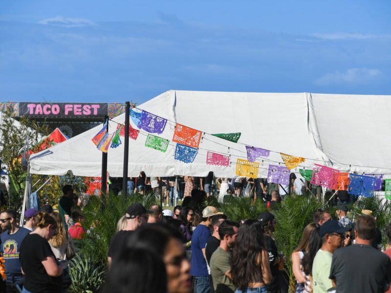 Crowd enjoying outdoor Cinco de Mayo festival with colorful decorations and tents.