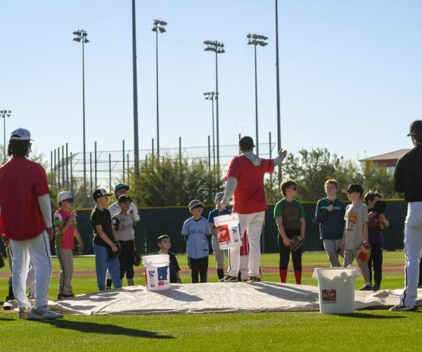 A group of children and adults engaged in an outdoor activity with buckets and a rope.