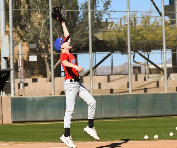 Baseball player jumping to catch a ball on the field.