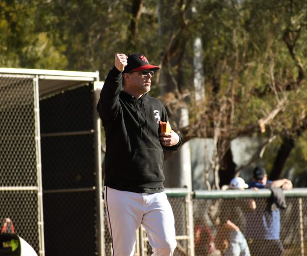 Man in baseball attire cheering with a drink in hand.