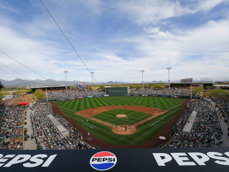 A packed baseball stadium with a game in progress under a partly cloudy sky.